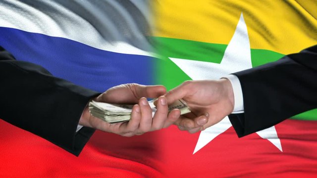 Russia and Myanmar officials exchanging tank for money, flag background, army