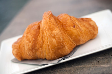 Closeup of traditional croissant in a white plate on table