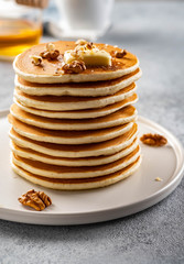 Tasty breakfast. Homemade pancakes with crushed walnut, honey or maple syrup on grey background.