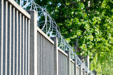 Wall or fence with barbed wire of sharp points that are difficult to climb over. limits area