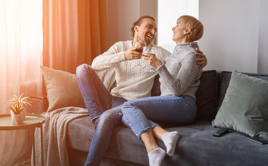 Happy couple clinking glasses on sofa