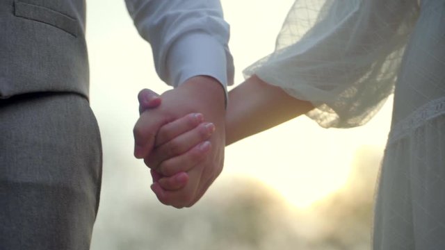 Couple holding hands at sunset in slow motion