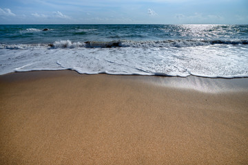 The beautiful waves of blue ocean on the fine sand beach on a sunny day.