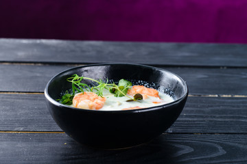 Vegetable cream soup with shrimps and croutons in white bowl close up