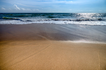 The beautiful waves of blue ocean on the fine sand beach on a sunny day.
