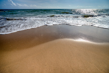 The beautiful waves of blue ocean on the fine sand beach on a sunny day.
