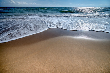 The beautiful waves of blue ocean on the fine sand beach on a sunny day.