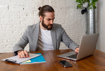 Portrait of happy attractive young businessman working on laptop looking confident