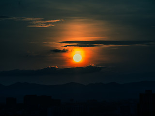 Obraz premium The orange sun and dark clouds over the city.