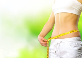 Young woman with measuring tape on her belly