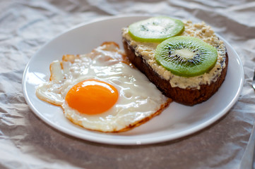 Delicious and healthy breakfast. Fried eggs and kiwi sandwich on white plate