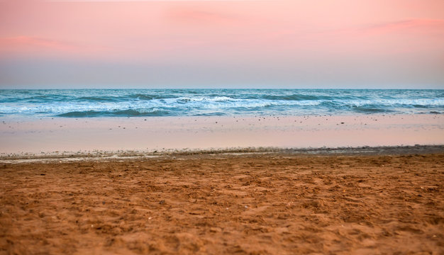 the shore of the beach at sunset with pink sky background