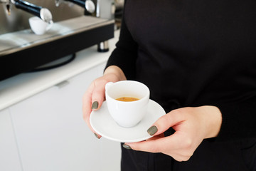 Close up shot of young beautiful barista woman with red hair wearing stylish black apron making cappucino hot beverage in hipster coffee place. Close up, copy space, background.