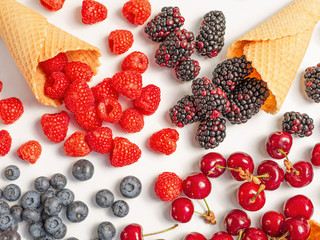 Flat lay summer fresh berries with waffle cones on white background