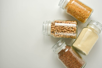 Various raw cereals in glass jar. Zero waste concept. Food storage. Flat lay. White background.
