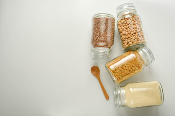 Various raw cereals in glass jar. Zero waste concept. Food storage. Flat lay. White background.