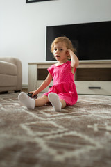 Little girl sitting on the floor indoors playing with a toy elephant