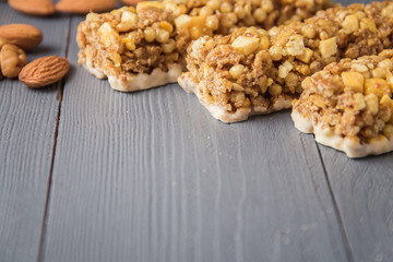 Granola bars cereal flakes with dried fruit, nuts on gray wooden table with copyspace.