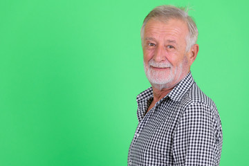 Closeup profile view of happy senior bearded man smiling and looking at camera