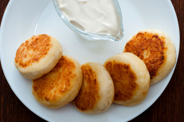 Fried cheese pancakes with sour cream view from above, close-up. For cafe or restaurant menu design.