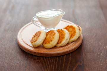Cheese pancakes with sour cream on a wooden board, horizontal format. For menu design and cafe advertising