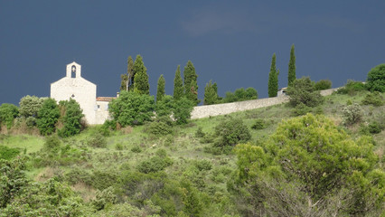 Fototapeta na wymiar Small white chapel in landscape under a stormy sky