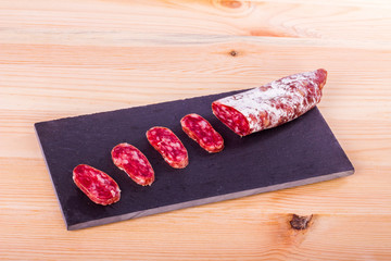 Spanish fuet, a dry sausage typical in Catalonia region, cut in slices on a wooden kitchen table