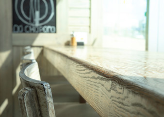 Fototapeta na wymiar Selected focus empty old rustic wooden table and bar chairs in street food coffee shop or restaurant blur background with bokeh image.