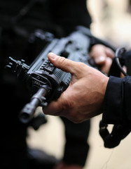 .Details with the hands of a man holding an automatic rifle.