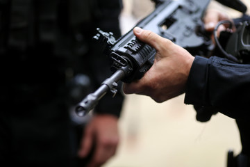 .Details with the hands of a man holding an automatic rifle.