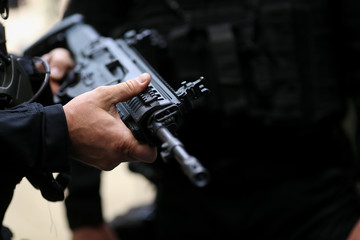 .Details with the hands of a man holding an automatic rifle.