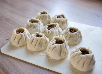 The process of making home-made dumplings. Raw homemade dumplings on a wooden board. Molding dumplings.
