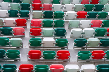 Rows of empty multicolored plastic stadium seats. Empty seats on tribune arena. Football stadium bleachers. Soccer, football stadium tribune without fans. Empty tribunes, game over. Sport Concept