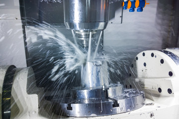 5-axis cnc milling machine at work with coolant under pressure and motion blur of streams..