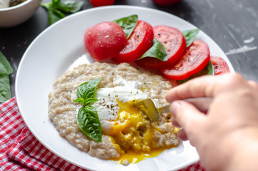 oatmeal with poached egg, tomatoes and basil. fresh tasty proper nutrition meal. healthy food for breakfast