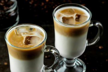 Ice latte or Iced coffee with milk and ice cubes in a glass beaker against a dark background. refreshing drink. summer drink.