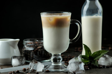 Ice latte or Iced coffee with milk and ice cubes in a glass beaker against a dark background. refreshing drink. summer drink.
