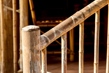 wooden handrail of bamboo summer house lit by sunlight close up.