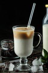 Ice latte or Iced coffee with milk and ice cubes in a glass beaker against a dark background....