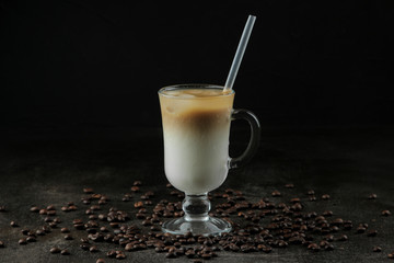 Ice latte or Iced coffee with milk and ice cubes in a glass beaker against a dark background....