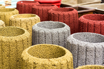 stone trash can in an assortment of new multi-colored garbage cans closeup.