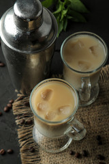 Ice latte or Iced coffee with milk and ice cubes in a glass beaker against a dark background. refreshing drink. summer drink.