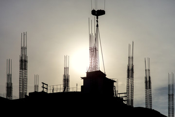 Obraz premium silhouette of a high-rise building under construction against the sun.