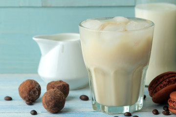 iced coffee with milk and ice cubes in a glass cup on a light blue background. refreshing drink. summer drink.