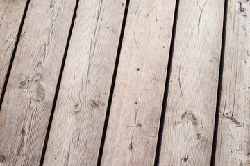 The surface of the old wooden floor, which is used outdoors. In the flooring large gaps between the boards. Due to weather conditions, a tree texture appeared on the docks.