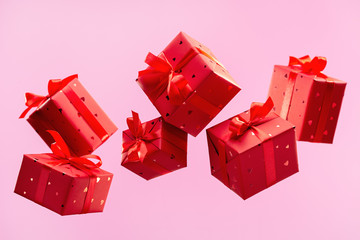 Many traditional gift boxes are falling on pink background. Festive season is bustle. Selection of...