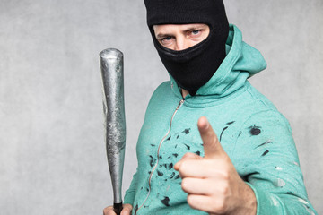 a masked hooligan holds a baseball bat in his hand