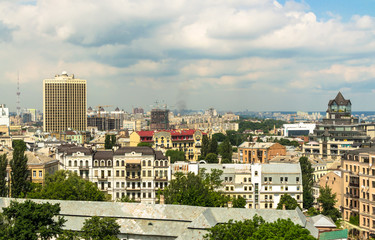 Fototapeta na wymiar Aerial view from St. Sophia Cathedral on buildings of historical center of Kiev. Beautiful Kiev roofs. In background - modern buildings of Kiev. Kiev - capital of Ukraine 