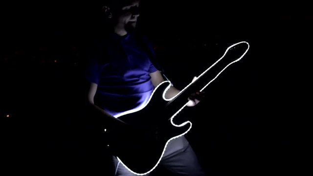 Guitarist plays guitar on the roof of the house. The guitar glows at night.