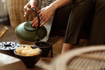 Gentle tranquil lady filling black ceramic cup with hot tea